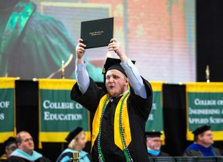 Arkansas Tech Announces 2018-19 Graduates A student proudly holds a diploma over his head after receiving it in the graduation ceremony