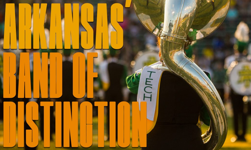 "Arkansas' Band of Distinction" graphic. The back of a sousaphone player during the opening number of a football game.